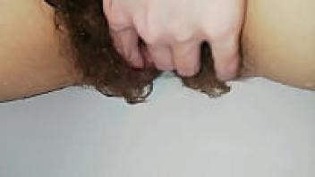 Close-up of a hairy, huge, clit that is grool moist